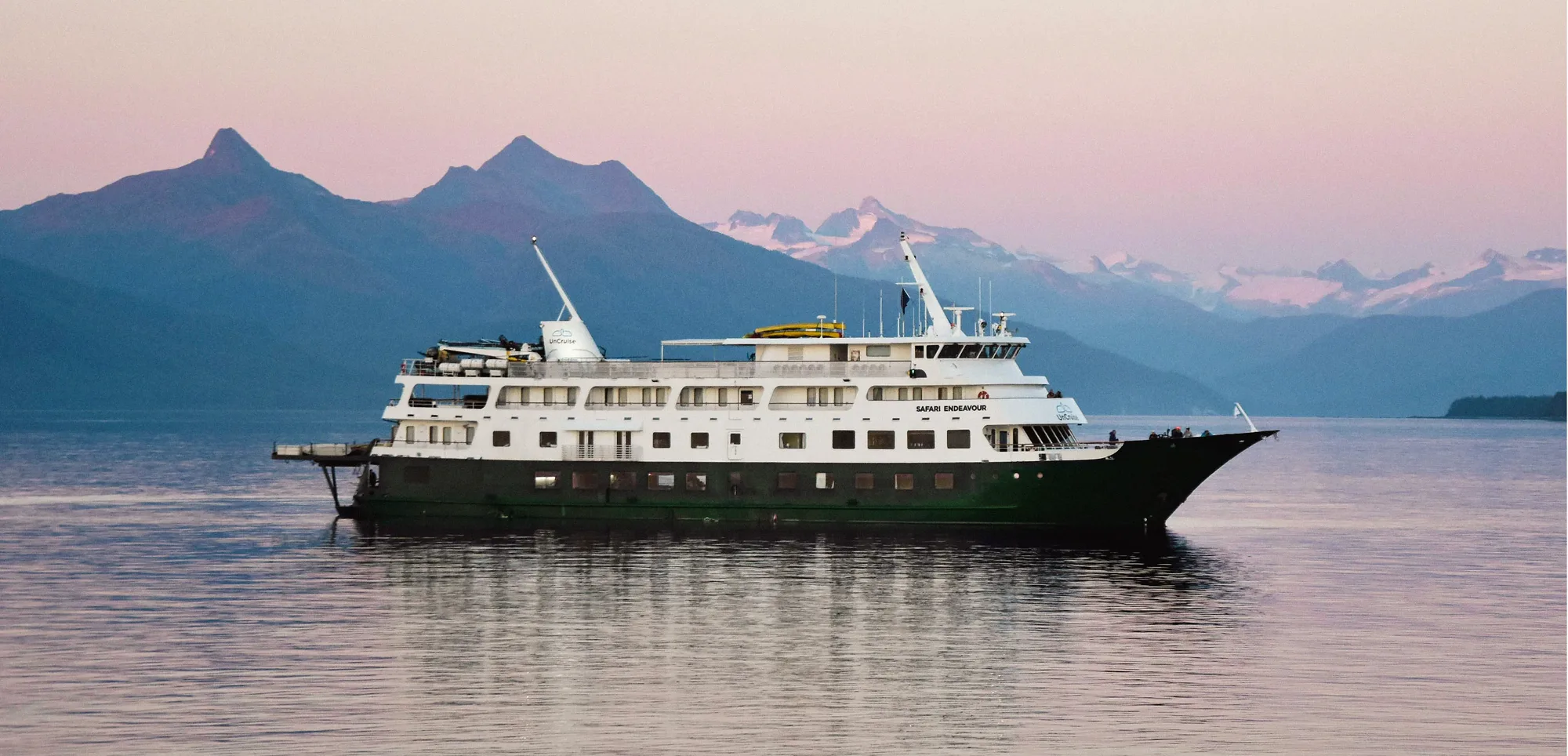 Small ship at anchor beneath mountains
